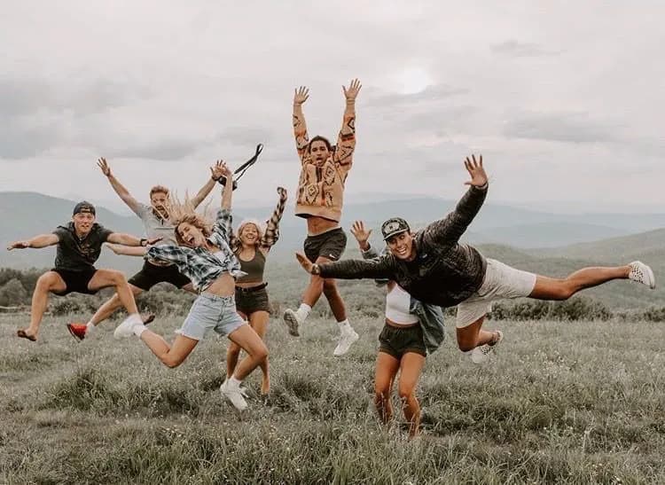 A group of friends jumping together in an open field.