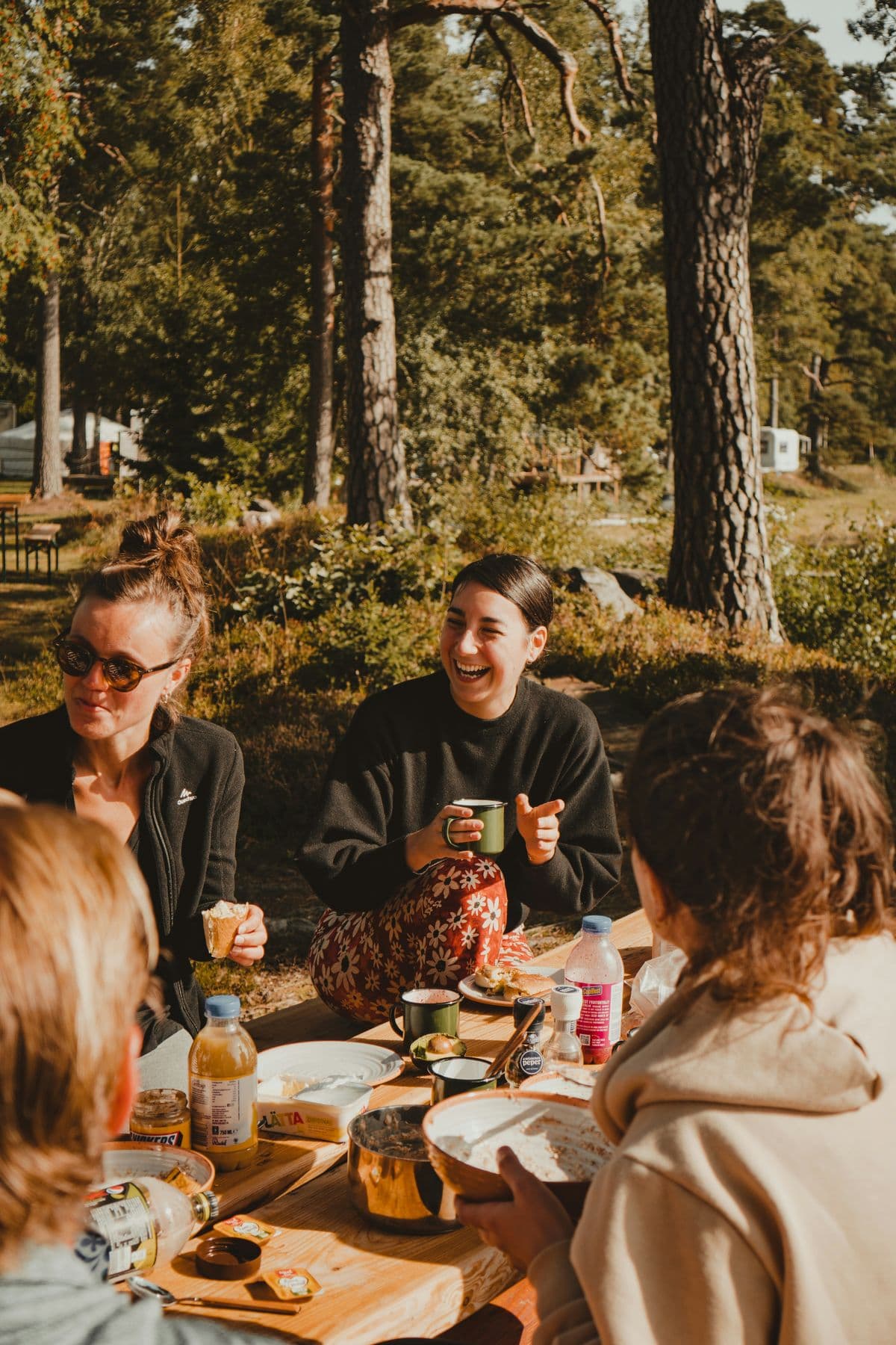 A small group gathered outdoors around a picnic table in conversation.