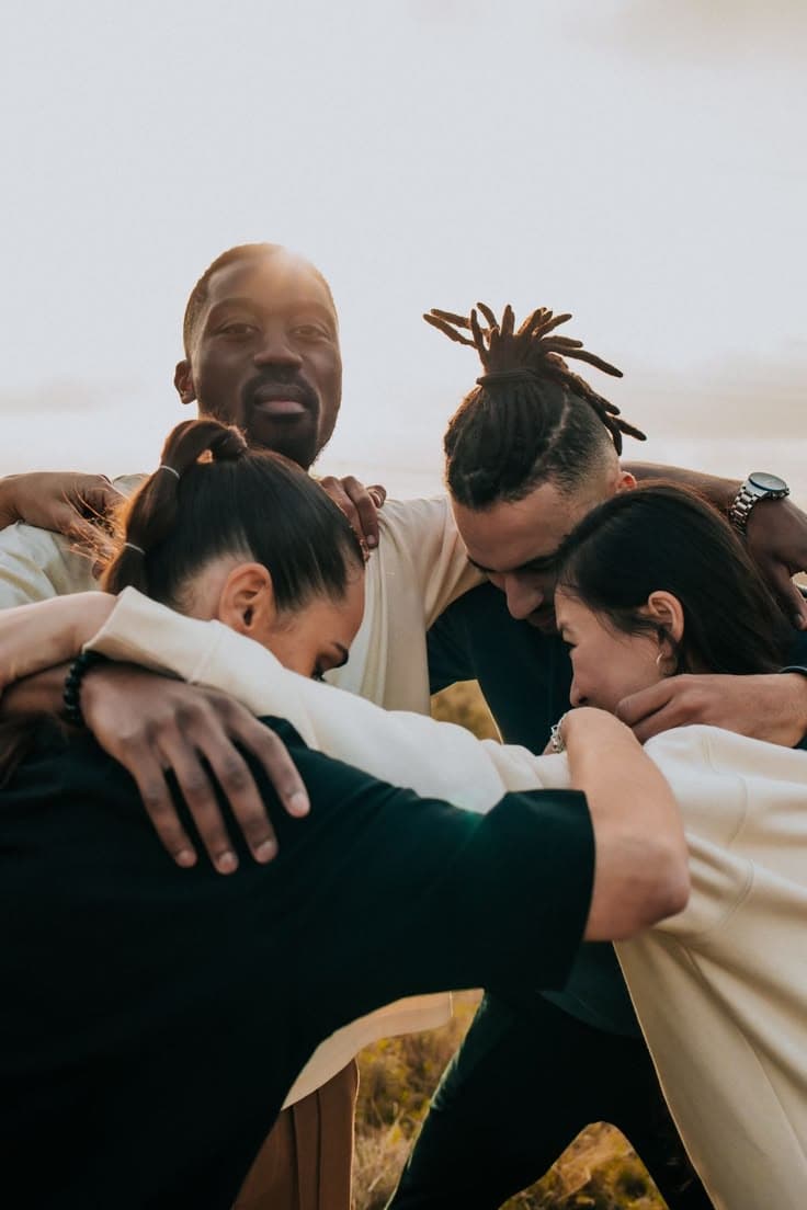A small group standing together in a supportive huddle outdoors.